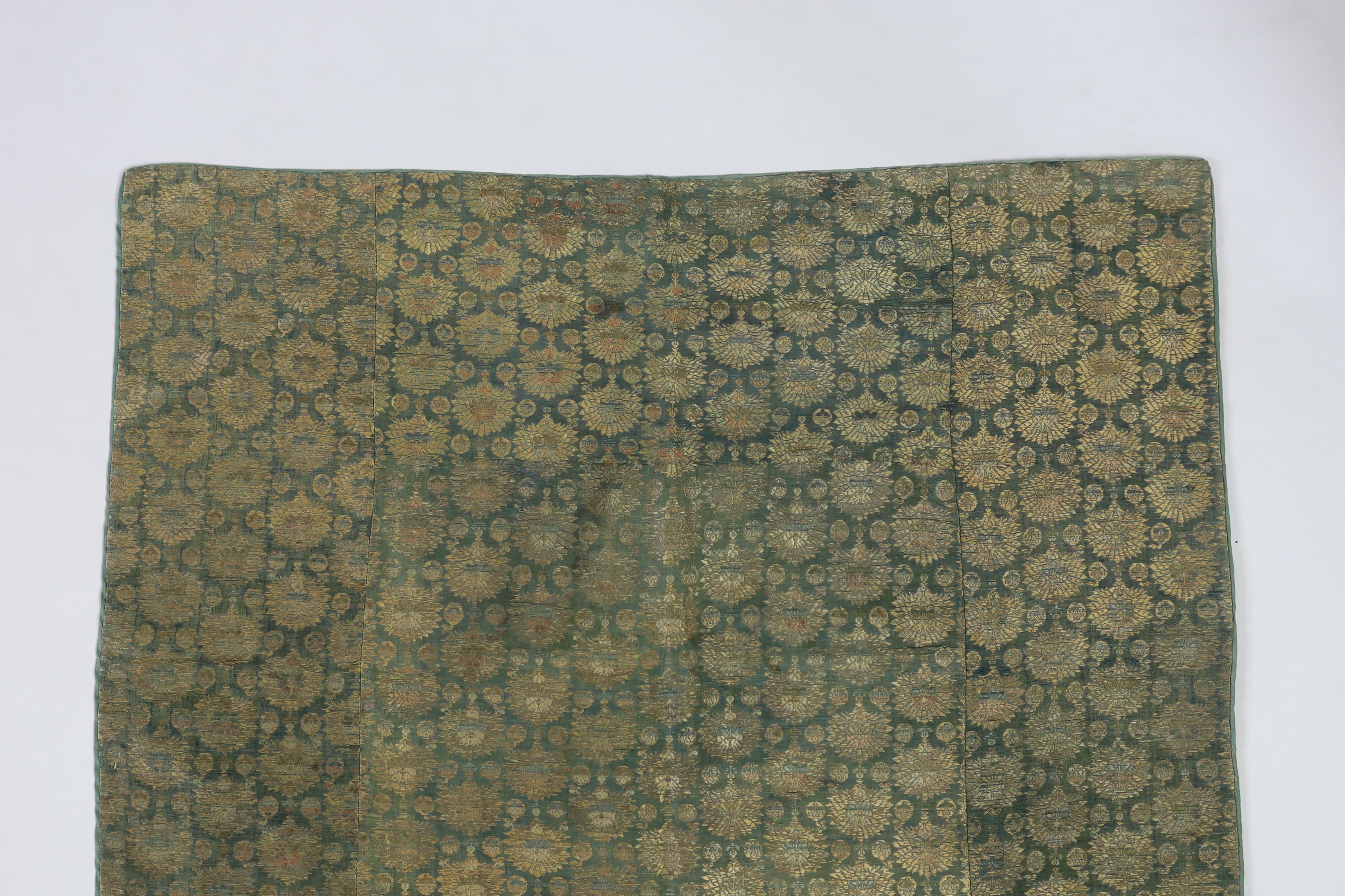 An 18th century, possibly Persian, fine green silk panel in gold and coloured silk threads, woven in narrow all over stripes of palmette and small floral spot motifs, joined together as three panels, with a silk backing,